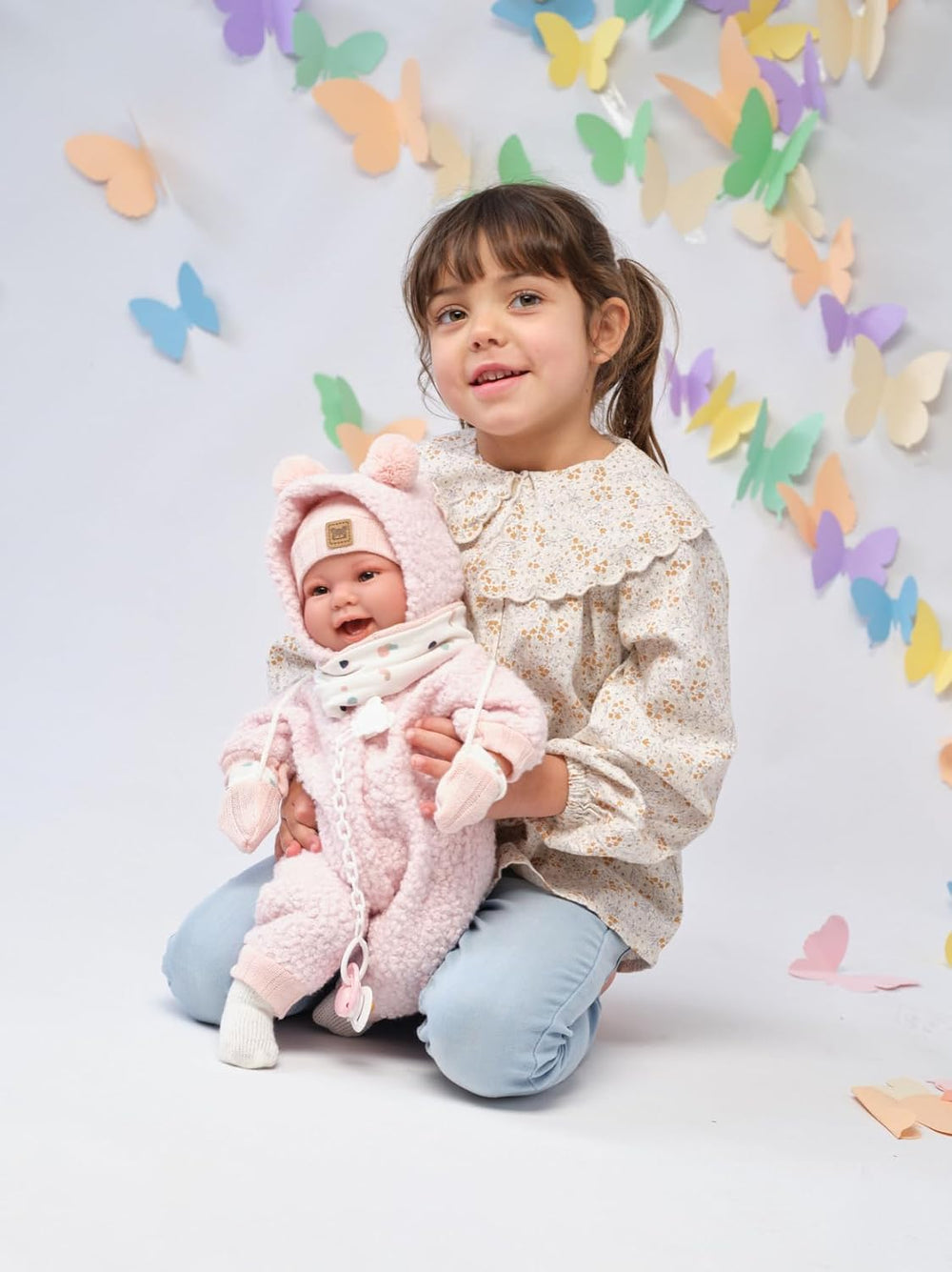 Llorens 1018480 Babypuppe Tala, aux yeux marron et au corps doux, Baby Puppe inkl. flauschigem rosa Tenue d'hiver, Schnuller, Schnullerkette, 44 cm